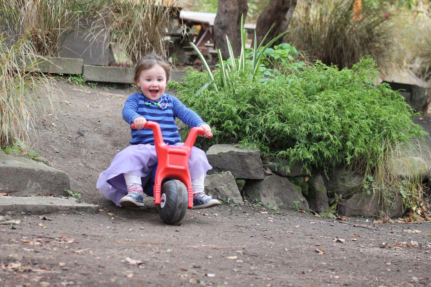 Kid smiling while riding toy bike