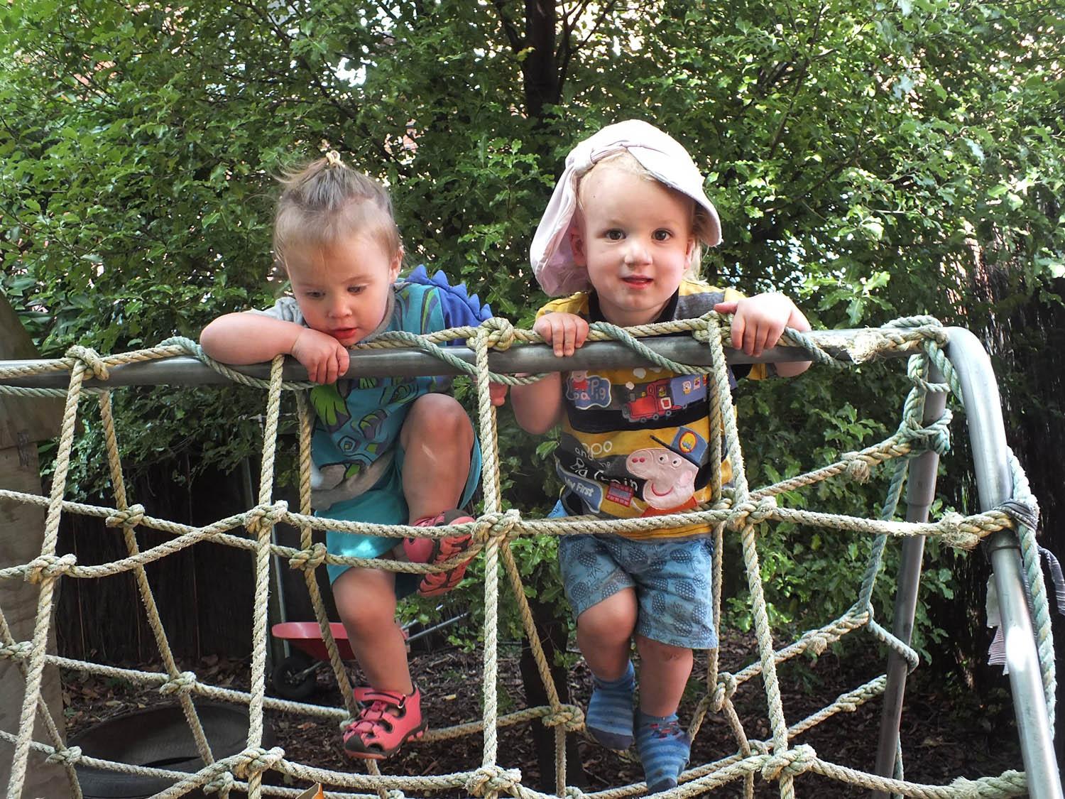 Children standing on playground climbing nets