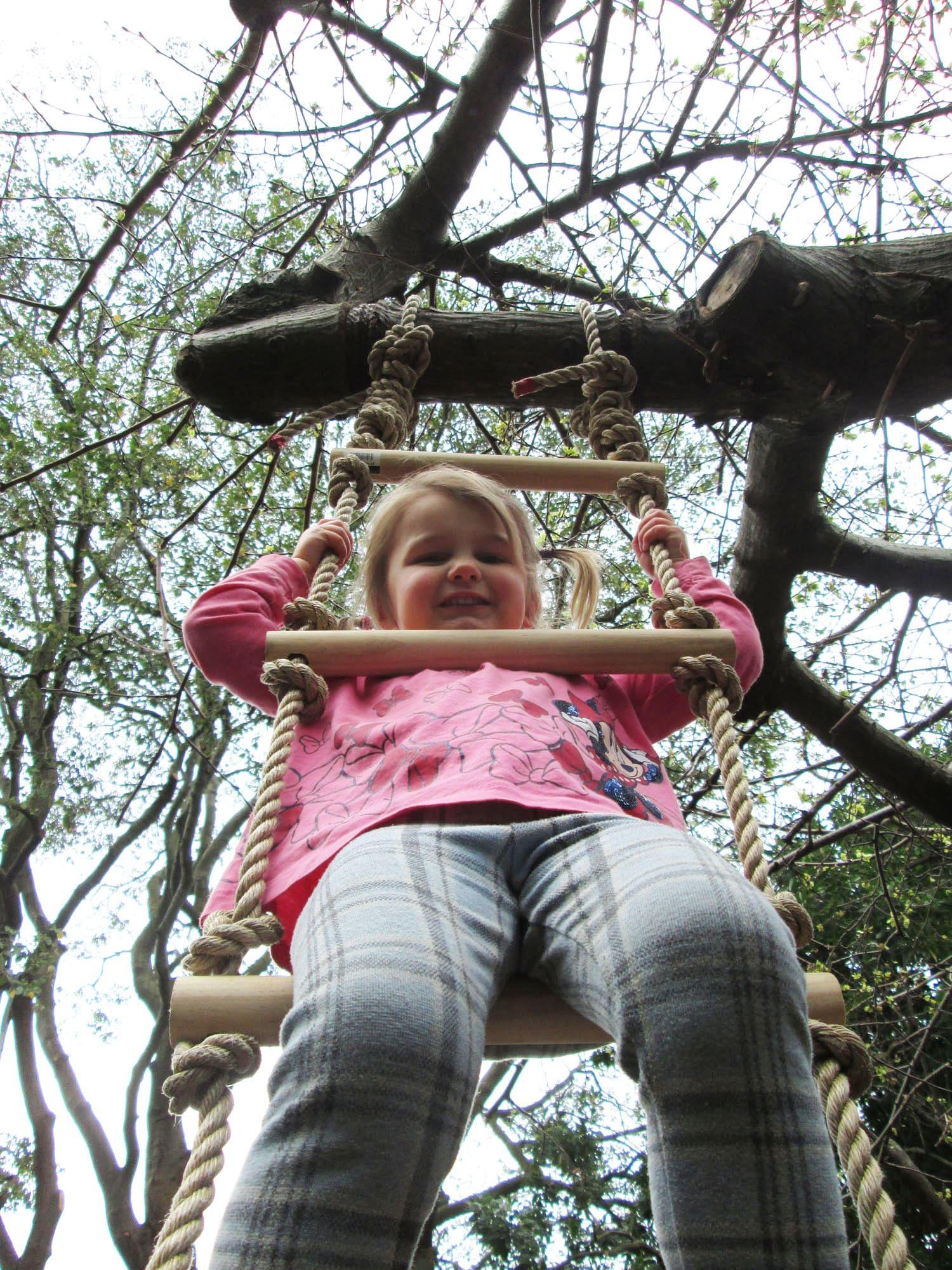 Child sitting on rope ladder